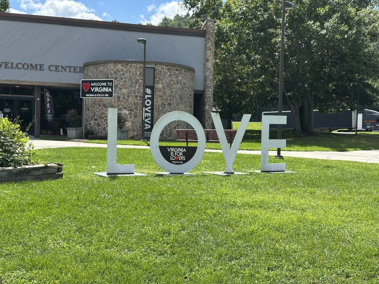 Giant white LOVE letters with a Virginia Is for Lovers sign in the O on the lawn of a Virginia welcome center